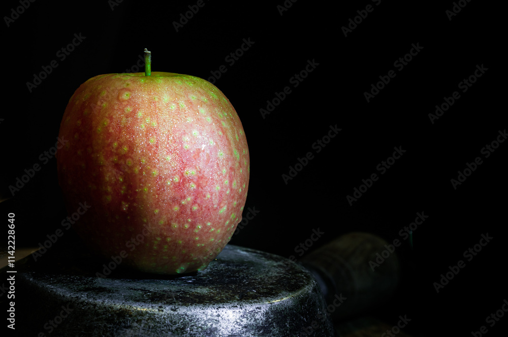A fresh kissabel apple fruit. Naturally pink flesh with a unique zesty taste in minimalist style on dark background. Light and Shadow, Space for text, Selective Focus.