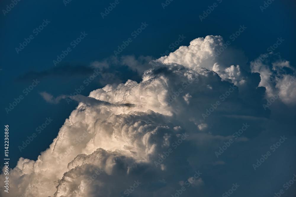 Na tle błękitnego nieba widoczna górna część skłębionej białej chmury cumulunimbus, często przynoszącej burze i intensywne opady deszczu.