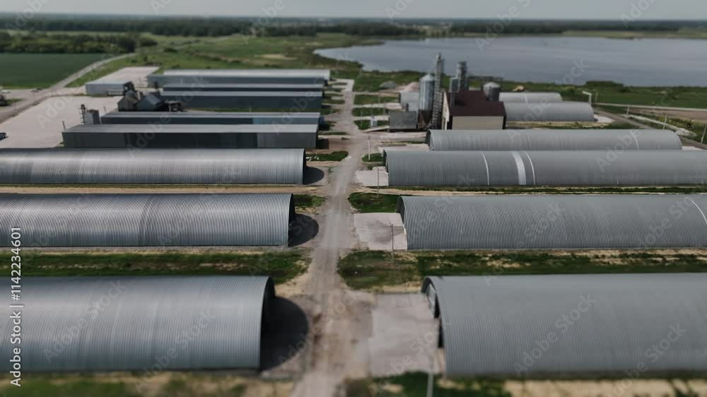 Aerial view of agro silos granary elevator and a large complex of barns and storage facilities. Agro-processing manufacturing plant for process of drying cleaning and storage of agricultural products. Aerial view of agro silos granary elevator and a large complex of barns and storage facilities. Agro-processing manufacturing plant for process of drying cleaning and storage of agricultural products.