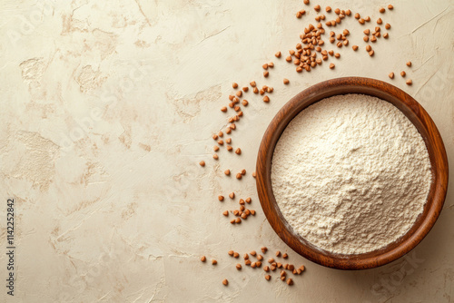 Buckwheat flour in a wooden bowl and raw buckwheat grain on beige monochrome background, close up. Alternative flour, gluten free flour, healthy nutrition photo