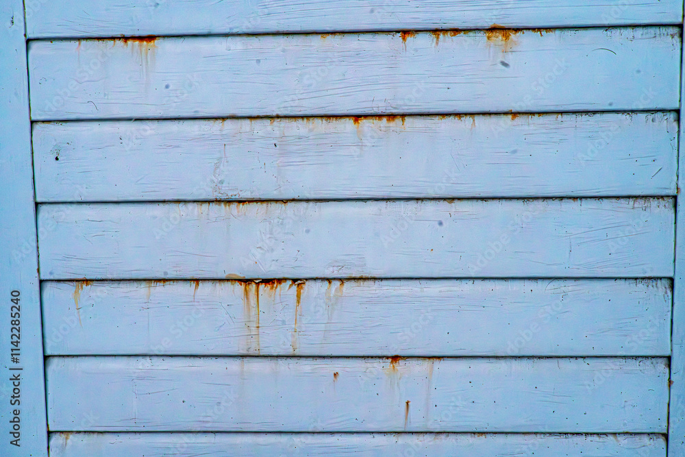 Fototapeta premium A weathered blue wooden wall with horizontal planks, showing rust stains and aged texture. The surface displays natural imperfections, scratches, and streaks, reflecting decay and vintage aesthetics. 