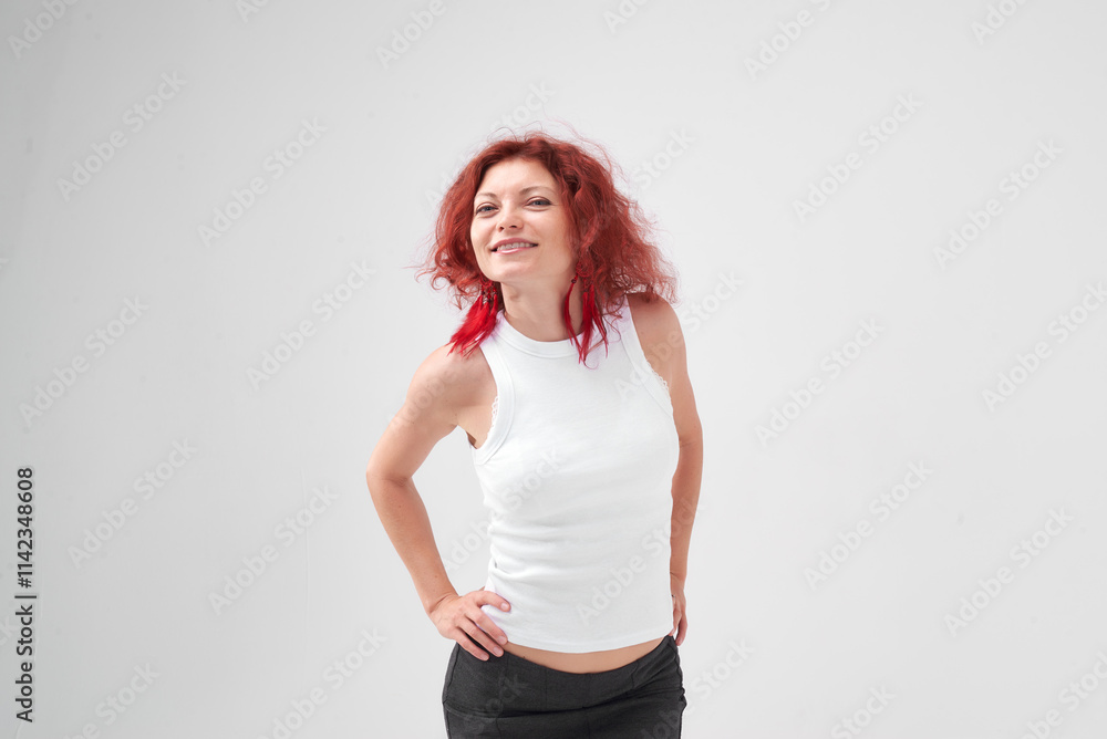 A woman with red hair poses for the camera with a smile on her face, she is wearing a white T-shirt and a black skirt. She has a beautiful figure. Fitness and healthy eating concept. A woman with red hair poses for the camera with a smile on her face, she is wearing a white T-shirt and a black skirt. She has a beautiful figure. Fitness and healthy eating concept.