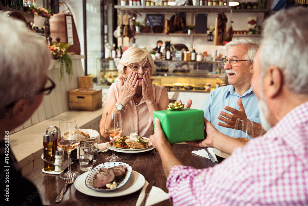 Senior couple celebrating birthday with a gift at a restaurant Senior couple celebrating birthday with a gift at a restaurant