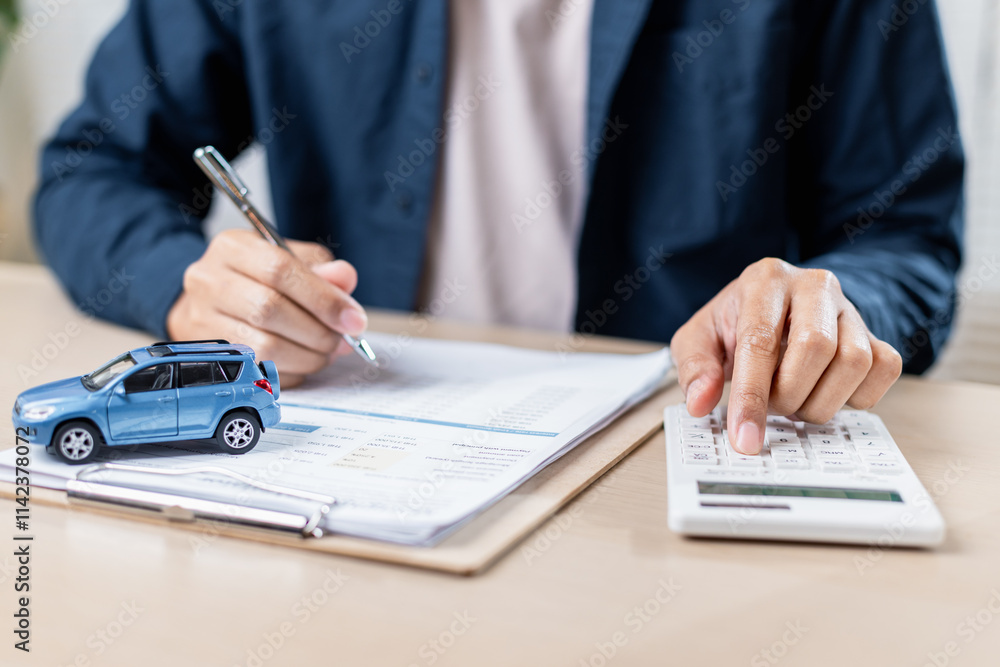 person calculating car expenses with model car on table person calculating car expenses with model car on table