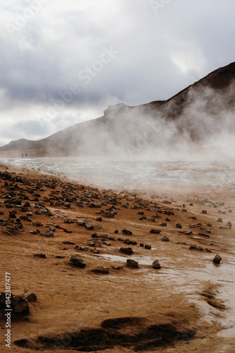 Steaming geothermal landscape under dramatic cloudy skies in Iceland