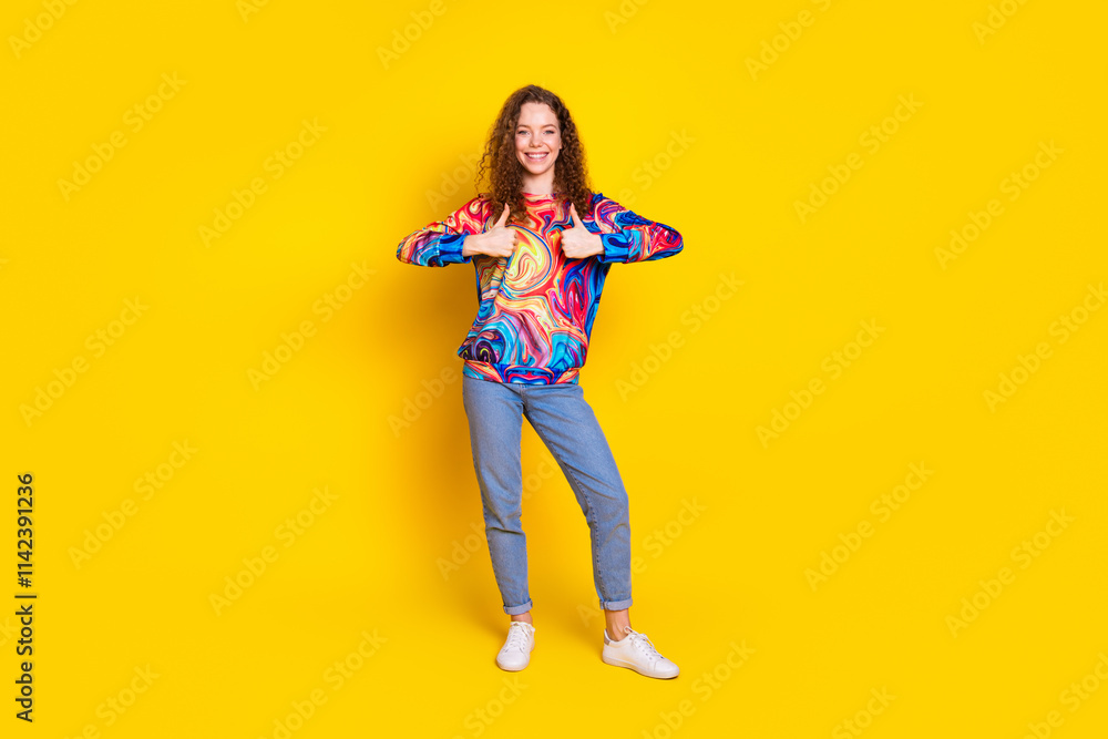 Joyful young woman with curly hair wearing a colorful pullover and jeans, standing confidently against a vibrant yellow background. Joyful young woman with curly hair wearing a colorful pullover and jeans, standing confidently against a vibrant yellow background.