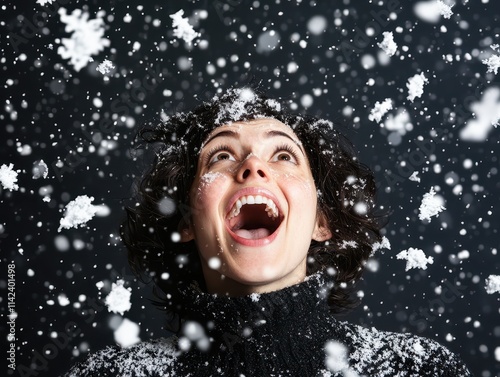 A joyful woman gazes upwards, mouth open in laughter, as snowflakes fall around her against a dark background.