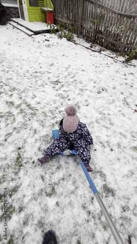 Dad rides a little girl on a shovel in the snow. Winter entertainment