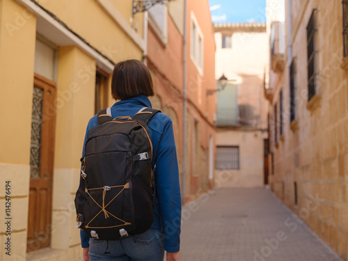 Young woman strolling through charming narrow streets of Denia, Alicante province, Spain, surrounded by historic Mediterranean architecture , enjoying peaceful atmosphere and cultural ambiance.