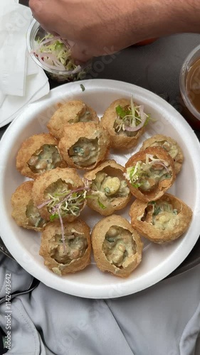 Preparing pani puri and gol gappe in a plate by adding salad into it. Adding salad to gol gappe or pani puri. Pani puri with salad and chatni. Pakistan street food golgappe with sauces and chatni. photo