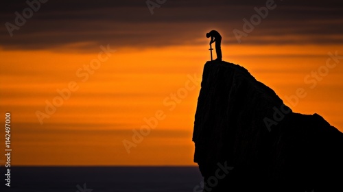 Knight's Sunset Vigil: Silhouetted knight stands on a clifftop, sword planted in the ground, as an fiery sunset paints the sky.  A powerful image of solitude, reflection, and the end of a battle. photo