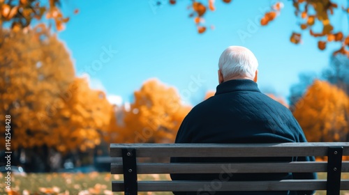 Fototapeta Naklejka Na Ścianę i Meble -  An older man sits on a park bench, looking out at the trees