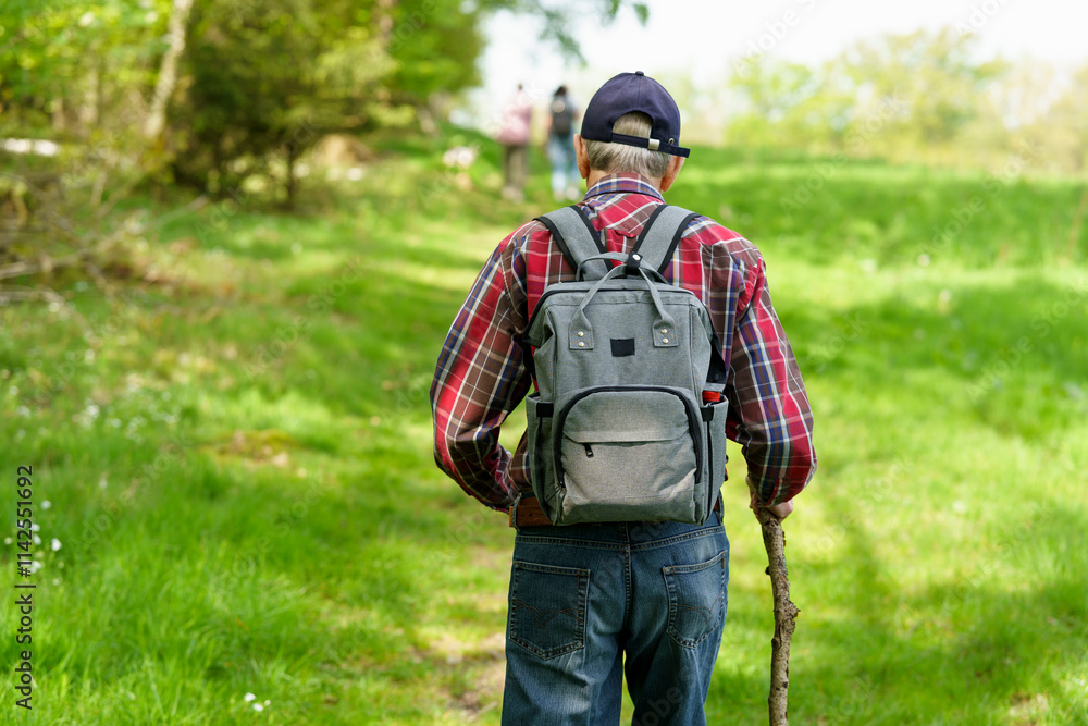 Back view of senior man with backpack standing in forest and not looking at camera Back view of senior man with backpack standing in forest and not looking at camera