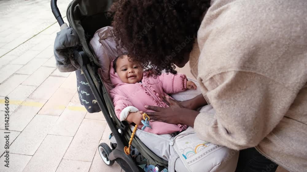 Happy baby girl lying in a stroller while her mother is making her laugh Happy baby girl lying in a stroller while her mother is making her laugh