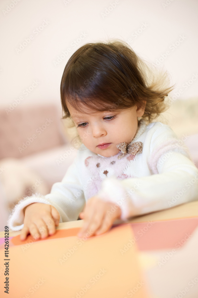 little child girl holding multi-color paper while sitting by table at home little child girl holding multi-color paper while sitting by table at home