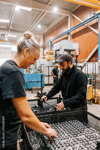 Multiracial female and male employees examining ball bearings in manufacturing factory photo