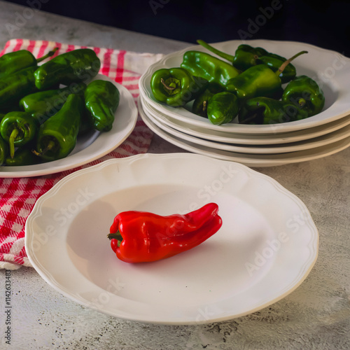 Dishes with raw peppers. One red pepper and the rest green