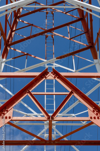 Low angle view of a large transmission tower with a distinctive geometric design, featuring red and white colors