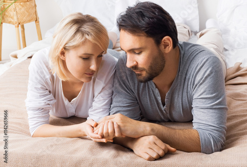 Image of closed eyes, leaned heads, hold hands man, woman, married couple, lay at bedroom, praying together before going to bed. Waiting child, pregnancy, problem issues, humility, plea concept photo. photo