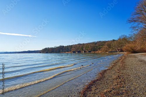 Shore, beach and wooden boat houses at the lake under the blue sky photo