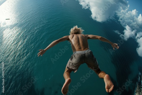 Wallpaper Mural Young man dives from cliff into the ocean on a sunny day under blue skies Torontodigital.ca