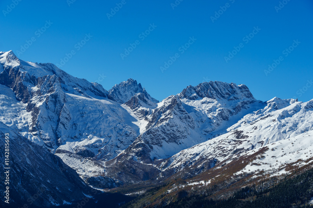 Fototapeta premium Picturesque landscape in Dombay with amazing snow-capped peaks and majestic blue slopes of North Caucasus Mountains. Mountain ski resort in Karachay-Cherkessia, Russia