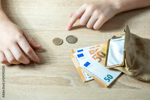 Teen holding wallet with Euro bills, symbolizing pocket money, savings or planning for future dreams, currency handling, monetary value photo