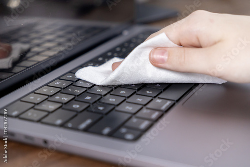 cleaning laptop keyboard with microfiber cloth for disinfection and maintenance photo