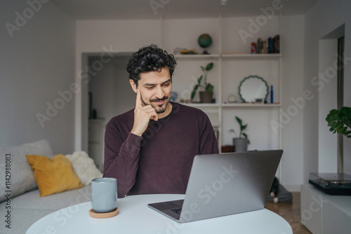 Young handsome middle eastern looking man using laptop computer in his home. 