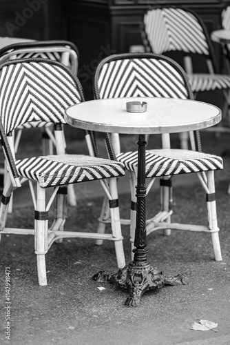 Traditional empty chairs and tables outdoors at a bistro restaurant in Paris France in black and white