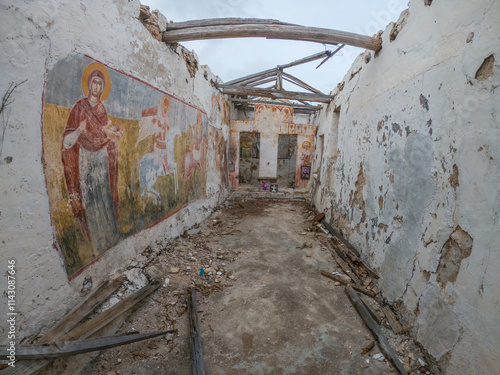 Ruined building interior with faded murals and damaged wooden beams. photo