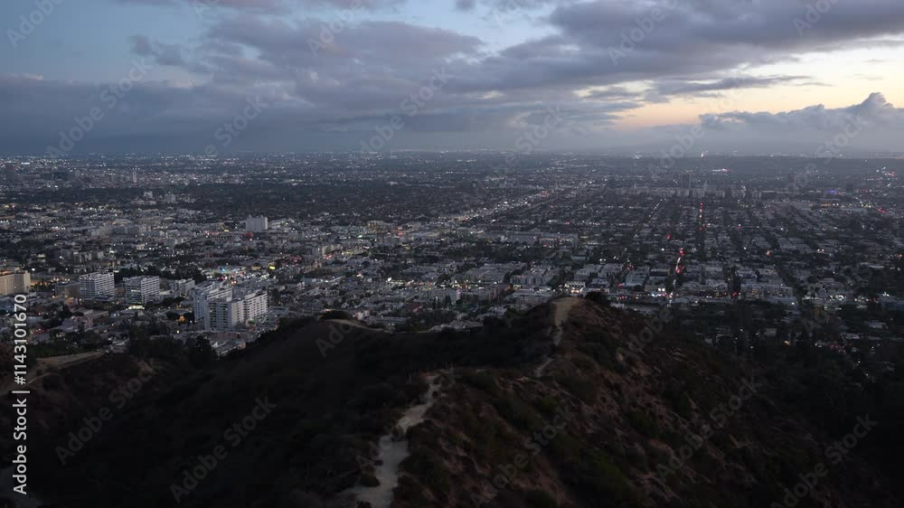Twilight view of Los Angeles from Runyon Canyon, with the city illuminated against a backdrop of clouds and darkness. Twilight view of Los Angeles from Runyon Canyon, with the city illuminated against a backdrop of clouds and darkness.