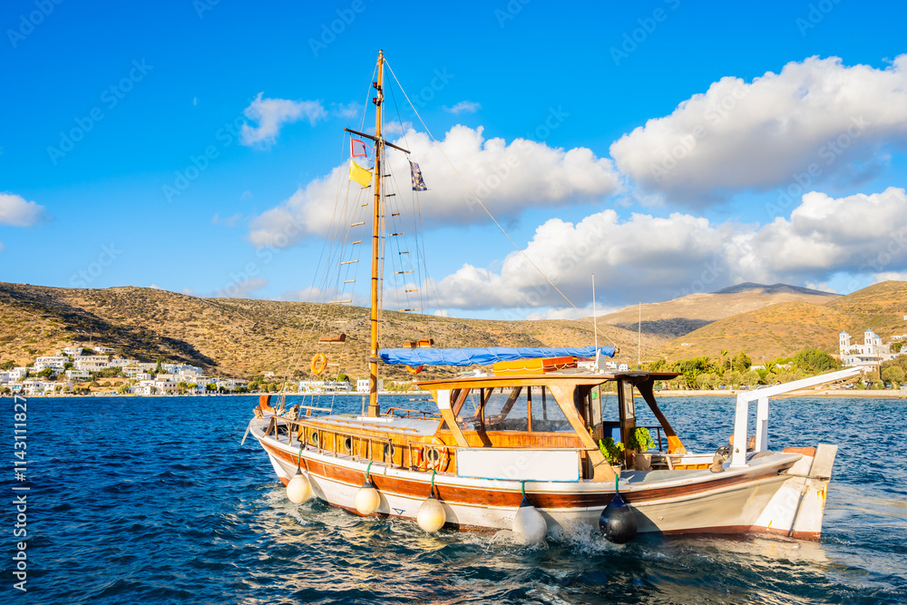 Traditional fishing boat sailing in Katapola sea bay with mountains in background, Amorgos island, Cyclades, Greece
