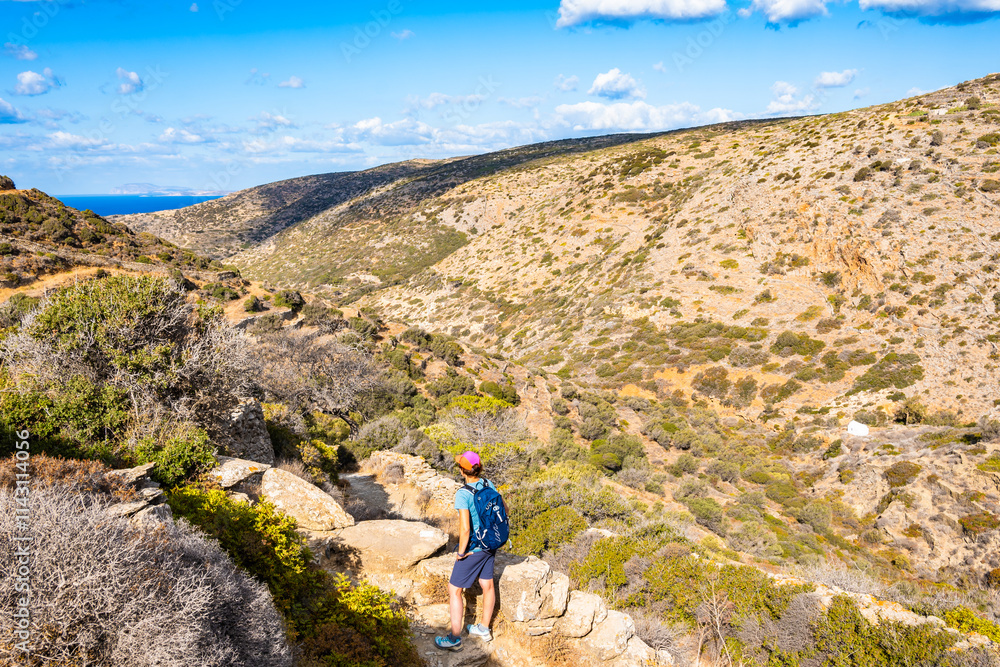 Woman tourist enjoying mountains view during trekking to Chora village from Katapola port, Amorgos island, Cyclades, Greece