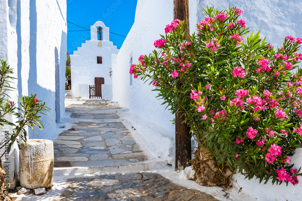 Narrow alley with flowers leading to white church in Chora village, Amorgos island, Cyclades, Greece