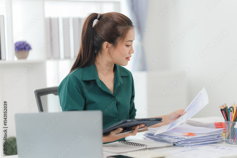 Focused Professional Woman Reviewing Documents at Desk Focused Professional Woman Reviewing Documents at Desk