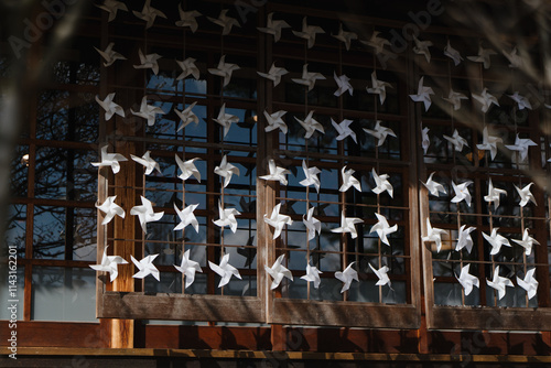 White paper pinwheels on wooden window in Japanese village. Concept of decoration, tradition, and peaceful cultural design