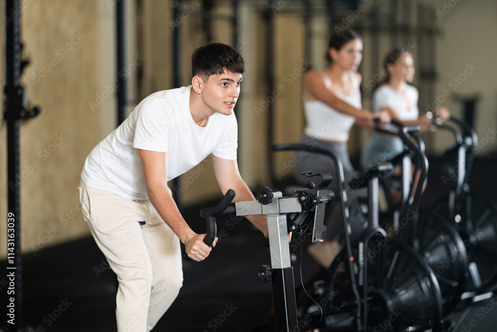 Young athletic man working out on exercise bike in gym Young athletic man working out on exercise bike in gym