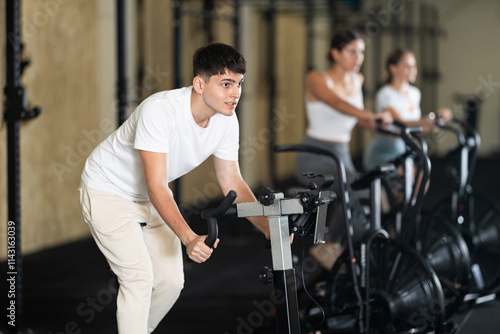 Young athletic man working out on exercise bike in gym