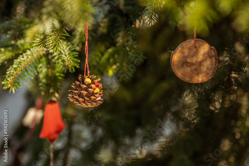 Detail Weihnachtsbaum mit Kiefernzapfen aufgehängt an roter Kordel und kleiner Astscheibe und roter Glocke aus Papier photo