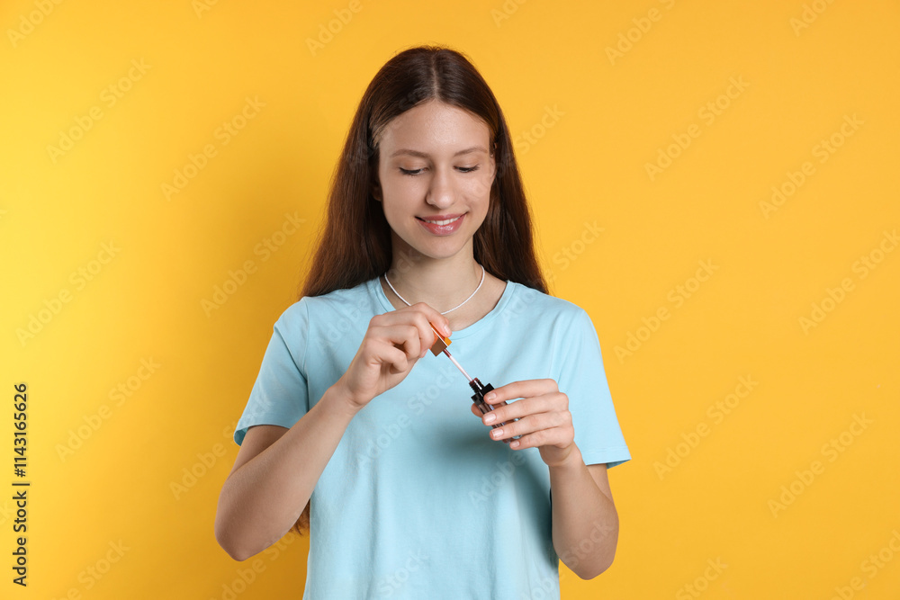 Smiling teenage girl with lip gloss on yellow background Smiling teenage girl with lip gloss on yellow background