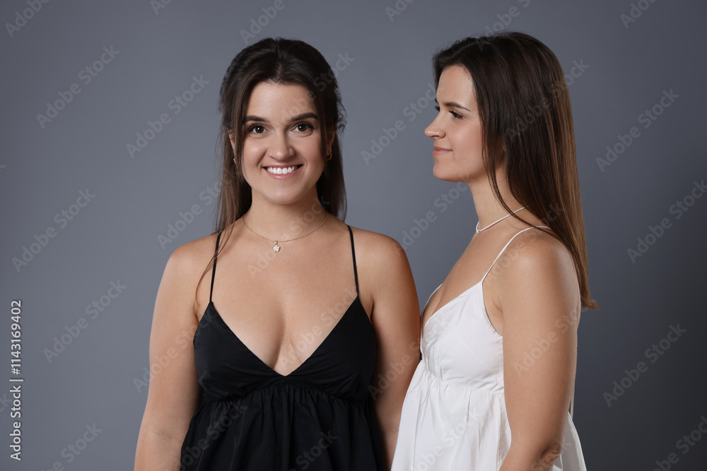 Portrait of beautiful twin sisters on grey background Portrait of beautiful twin sisters on grey background