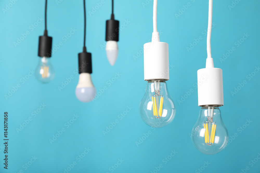 Light bulbs hanging on cords against light blue background Light bulbs hanging on cords against light blue background