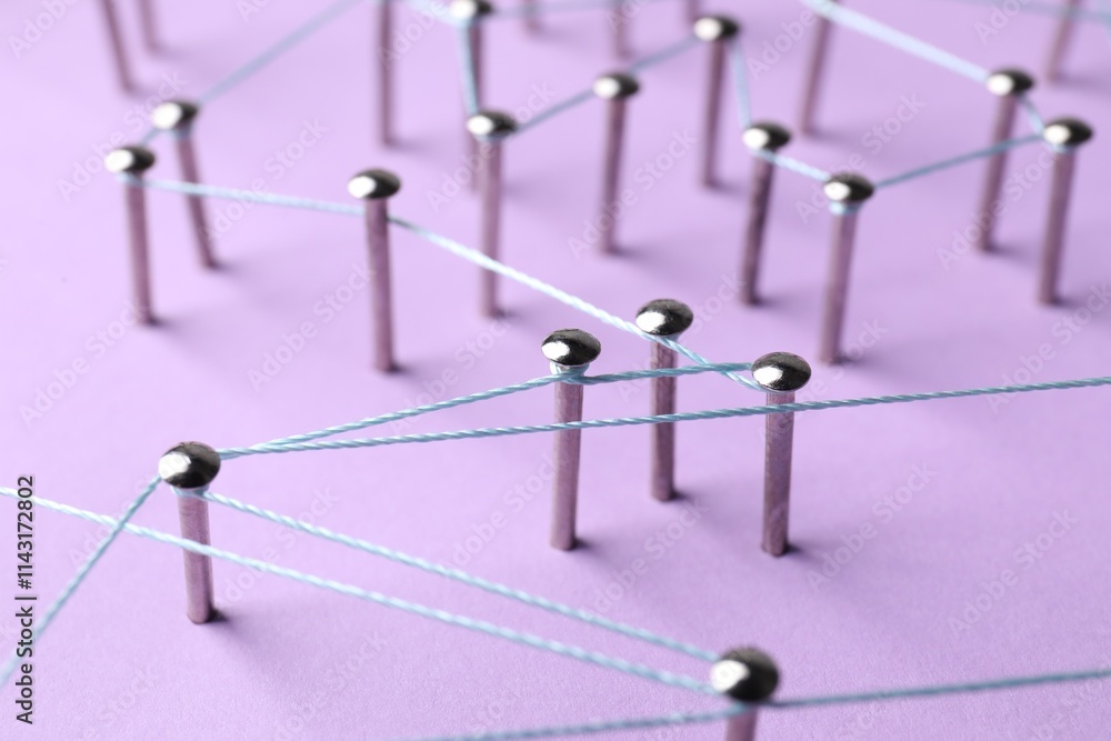 Network connection. Nails linked together by thread on violet background, closeup Network connection. Nails linked together by thread on violet background, closeup