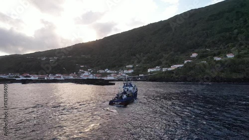 Imagens de um atuneiro navegando nas águas cristalinas ao largo da Ilha do Pico, nos Açores, com a majestosa ilha ao fundo.