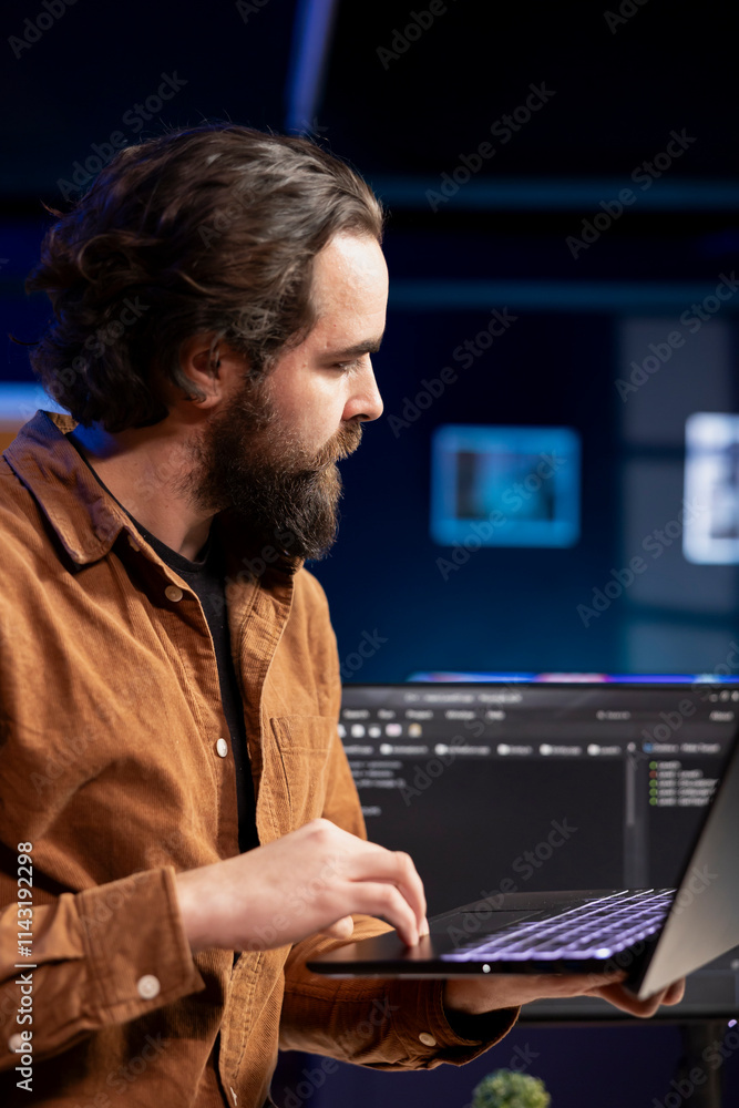 Computer engineer crosschecking between laptop and monitor, implementing security measures to protect company systems. IT worker comparing software code between notebook and PC Computer engineer crosschecking between laptop and monitor, implementing security measures to protect company systems. IT worker comparing software code between notebook and PC