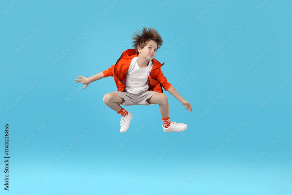 Happy little boy jumping on light blue background Happy little boy jumping on light blue background