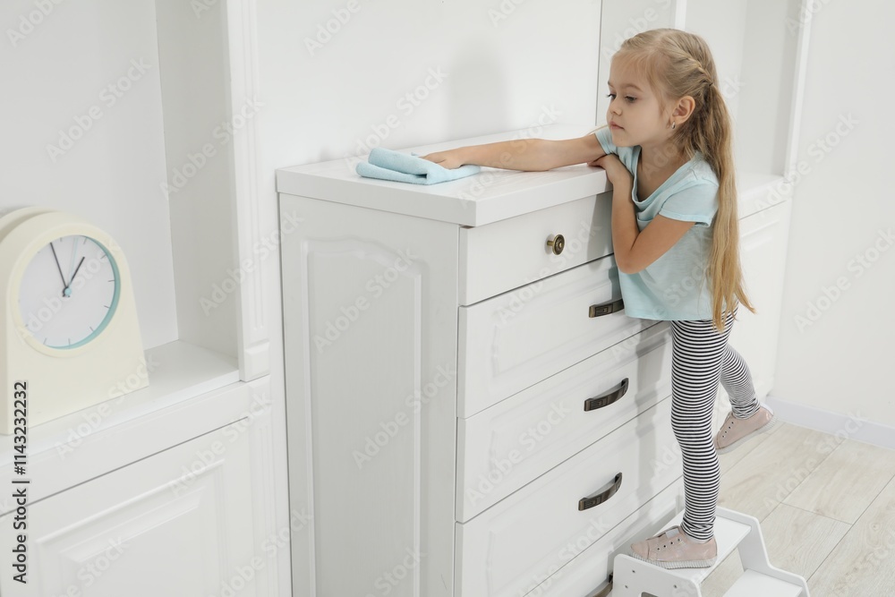 Little helper. Cute girl wiping dust from chest of drawers at home Little helper. Cute girl wiping dust from chest of drawers at home