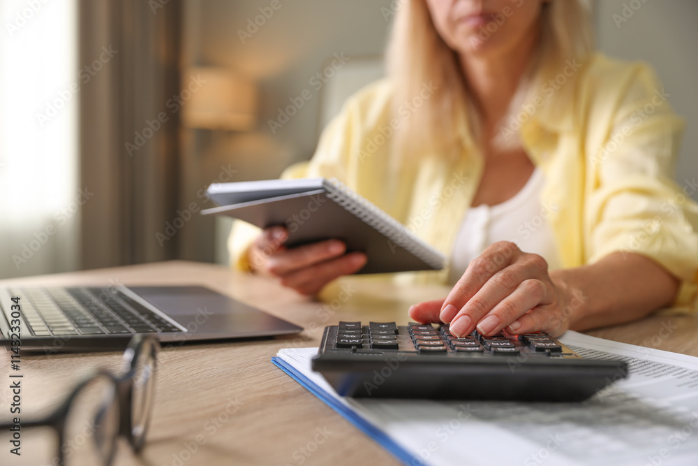 Budget planning. Woman with notebook using calculator at table indoors, closeup Budget planning. Woman with notebook using calculator at table indoors, closeup