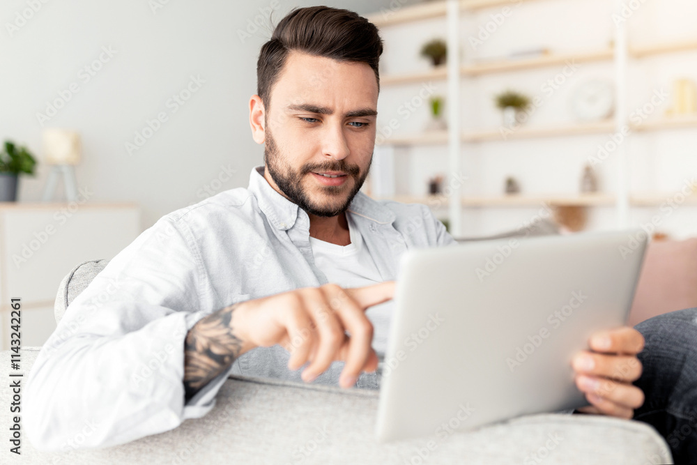 Closeup of handsome man reclining on sofa, using modern pad at home interior. Happy guy resting on couch in living room, using nice mobile app on digital tablet, copy space, panorama Closeup of handsome man reclining on sofa, using modern pad at home interior. Happy guy resting on couch in living room, using nice mobile app on digital tablet, copy space, panorama